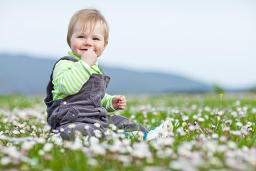 Happy baby in flowers field