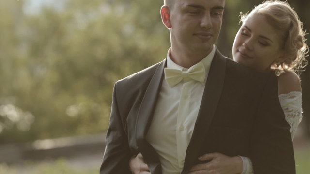 Gentle bride hugs groom aback