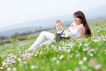 Happy mother are playing with baby in flowers field