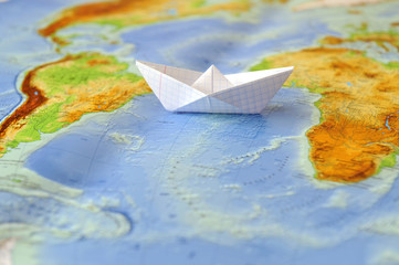 Paper boat on a background map of the world
