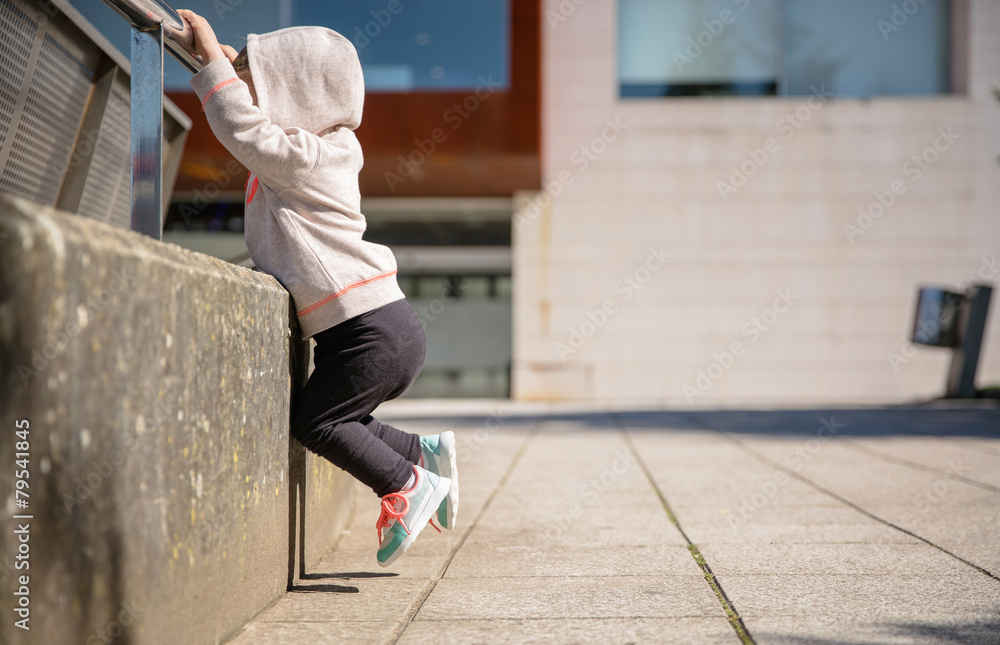 Wall mural Little girl with sneakers and hoodie training outdoors - Wall murals