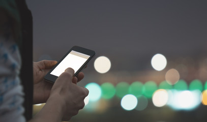 Typing messages - with defocused city lights.