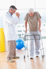 Fototapeta premium Senior man on zimmer frame with therapist