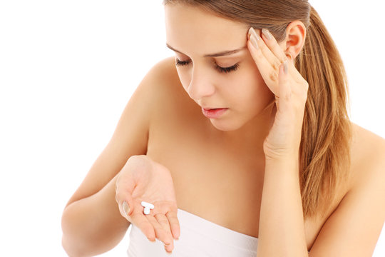 Woman with headache holding pain killers