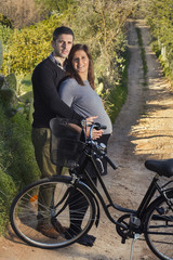 Close up view of a expecting happy couple on a bicycle.