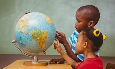Kids pointing at globe in classroom