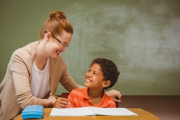Teacher assisting little boy with homework in classroom