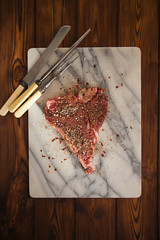 beef steak t-bone with vintage meat fork on marble backdrop