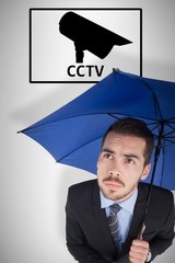 Composite image of anxious businessman under umbrella looking up