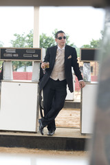 Handsome young groon standing at gas station with drink