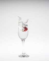 fresh strawberry dropped into water with splash on white backgro