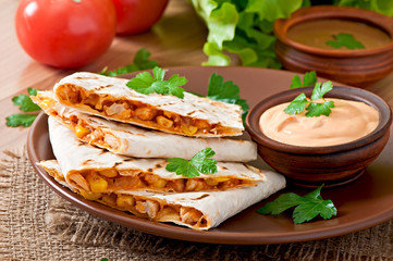 Mexican Quesadilla sliced with vegetables and sauces on the tabl