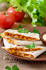 Mexican Quesadilla sliced with vegetables and sauces on the tabl