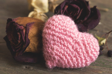 pink knitted heart and dried red roses