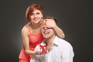 romantic woman covering her boyfriend's eyes, with gift