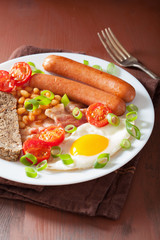 english breakfast with fried egg sausages bacon tomatoes beans