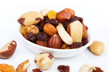 Mixed nuts and sultanas on a plate on a white background