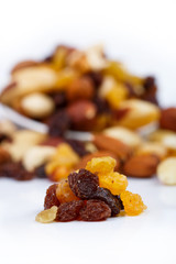 Mixed nuts and sultanas on a plate on a white background