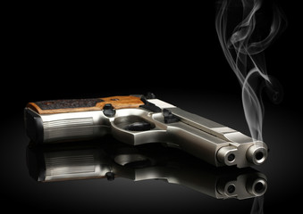 handgun on black background with smoke - obrazy, fototapety, plakaty
