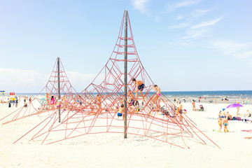 Children in the summer on the beach by the sea climb ropes