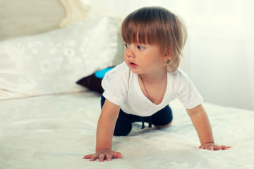 Naklejka premium Little boy crawling on the big bed