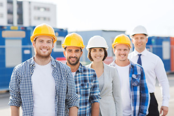 group of smiling builders in hardhats outdoors