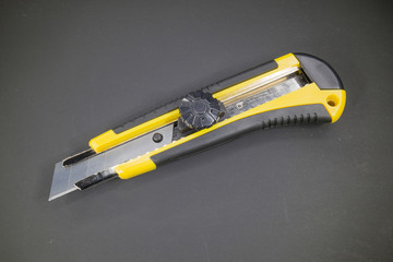 Utility knife with yellow plastic handle and black rubber insert