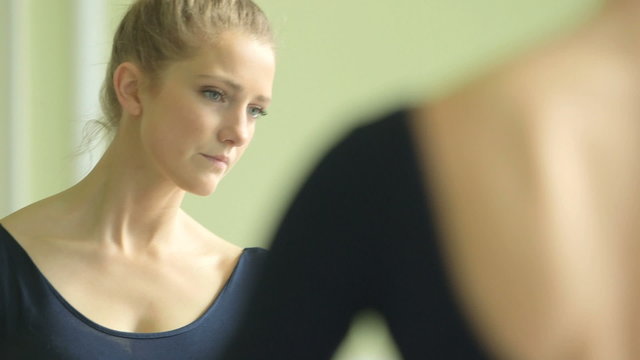 Female Ballet Dancer stretches and practices using the barre and studio mirror