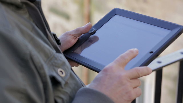 Close up of casual man holding digital tablet, outdoor