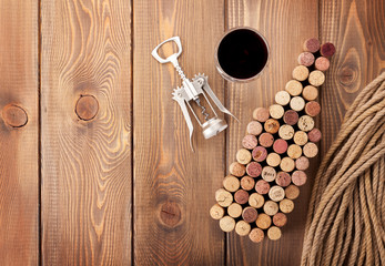 Wine bottle shaped corks, glass of red wine and corkscrew