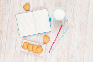 Cup of milk, heart shaped cookies and notepad