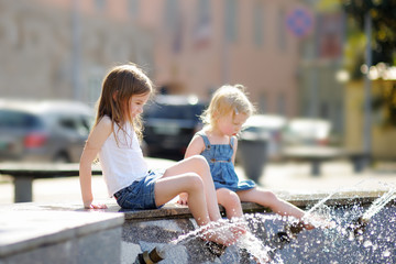 Two sisters having fun in a city fountain