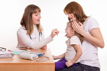 The doctor examines throat of a child sitting on hands