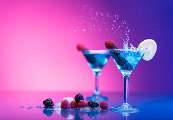 Colourful cocktails garnished with berries, water splash