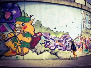 Junge fährt Roller an Graffiti Wand