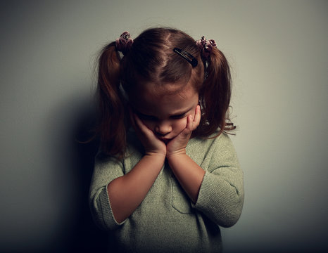 Sad crying alone kid girl on dark background