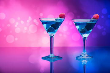 Colorful cocktails with berries, light effects background