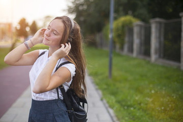 Girl enjoying music with headphones in the mild sunshine.