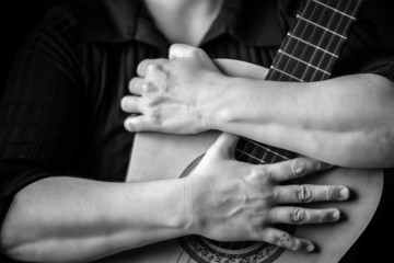 Hands hugging an acoustic guitar