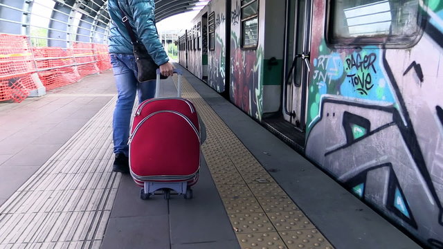 Young man with a baggage on the platform of a train station. Camera tracking