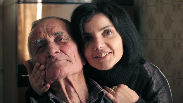 beautiful woman caresses and kisses his grandfather looking at the camera
