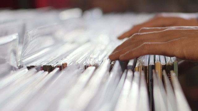 CU A Young Man's fingers flick through a rack of vintage records