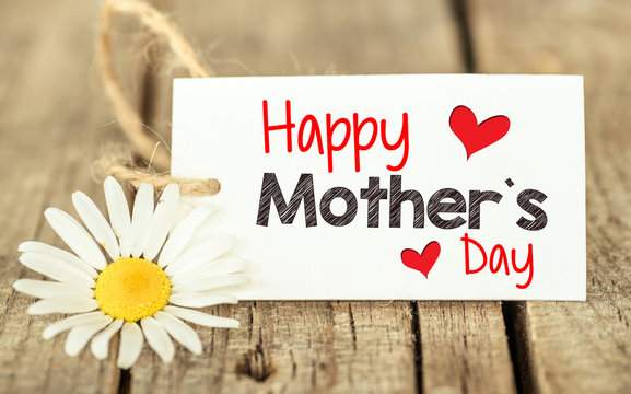 Flowers and label with Happy Mother's day on wooden background