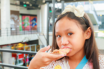 Asian girl child eat pizza in restaurant