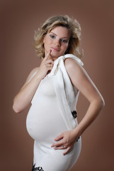 Attractive pregnant girl against beige background.