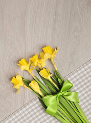Bunch of narcissus flowers on cotton napkin on wood