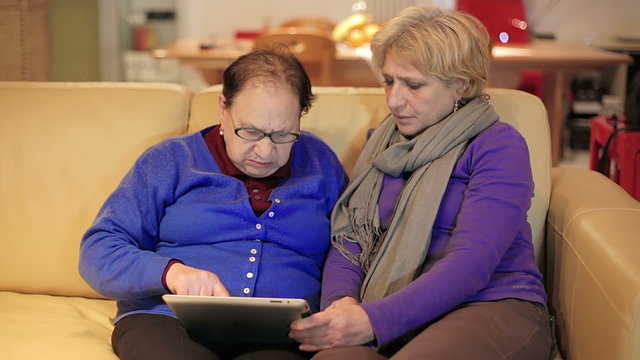 woman teaches her mother use with tablet computer - senior lifestyle