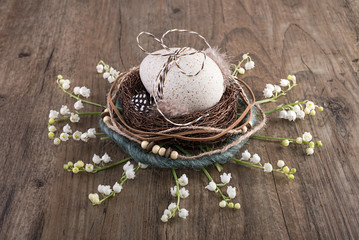 Decorative Easter nest on oak table with egg and spring flowers