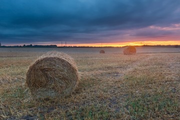 Straw bales on field against sky