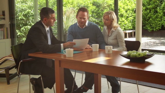 Wide, Track shot off couple signing contract at dinning table and handshake financial advisor